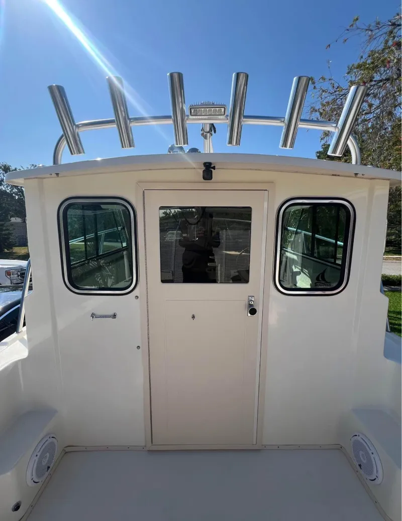 Slide: The Image of 2008 Parker 2120 Sport Cabin boat with rod holders and cabin door under clear sky. - 14