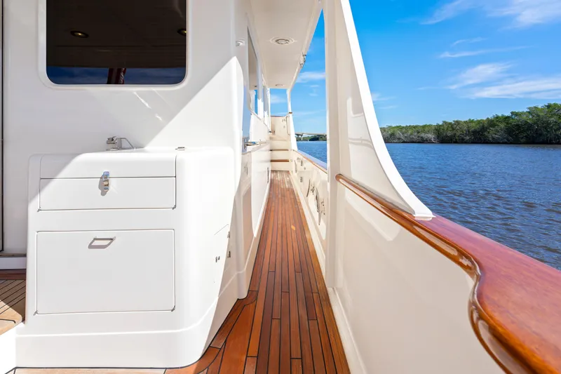 Slide: The Image of Side deck of 2023 Fleming 65 yacht with wooden flooring, overlooking serene water and blue sky. - 49