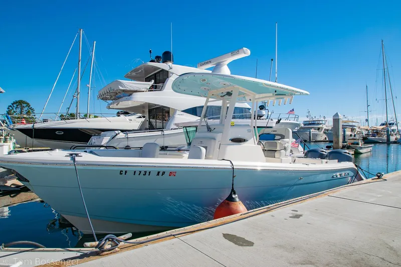 Slide: The Image of 2018 Cobia 240 CC boat docked at a marina under clear blue skies. - 1