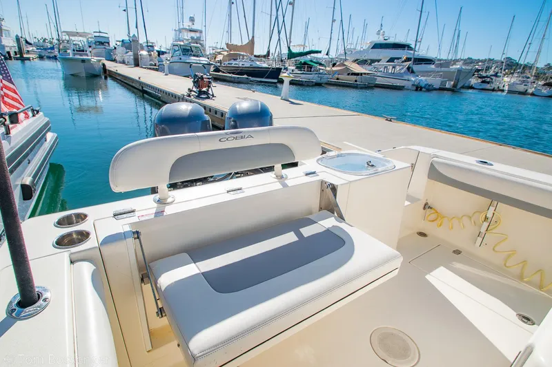 Slide: The Image of 2018 Cobia 240 CC boat docked at marina with seating and twin engines. - 13