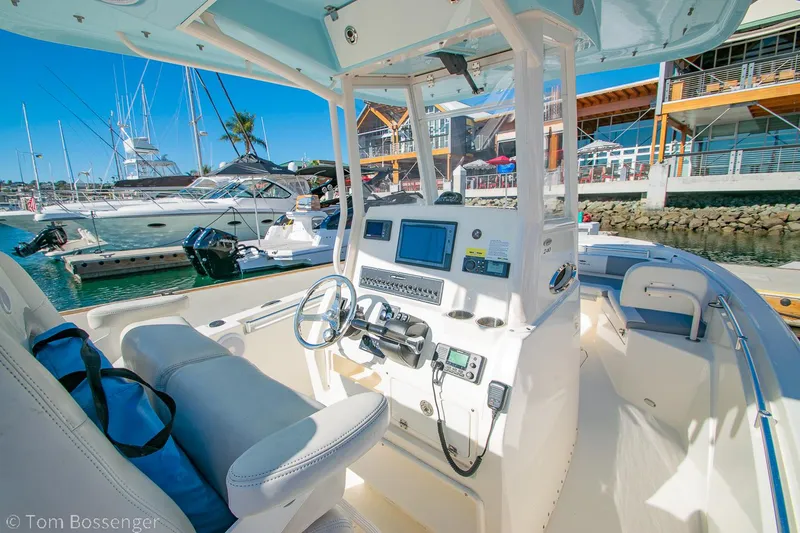 Slide: The Image of 2018 Cobia 240 CC boat interior at marina, featuring helm and navigation equipment. - 8
