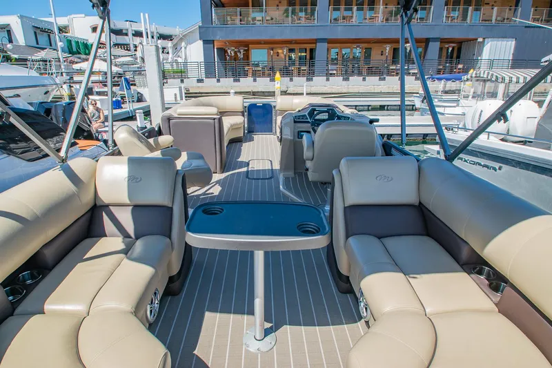 Slide: The Image of 2021 Manitou Oasis SHP pontoon boat interior with luxurious seating and table, docked at marina. - 37