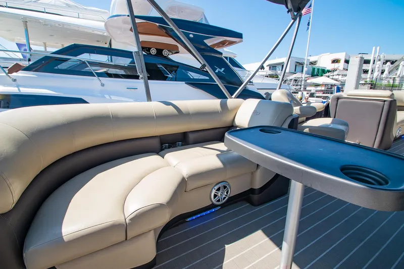 Slide: The Image of 2021 Manitou Oasis SHP pontoon boat with luxurious seating and table, docked at marina. - 44