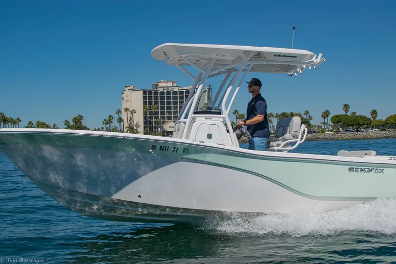 Slide: The Image of 2021 Sea Fox 248 Commander boat cruising on a sunny day near a coastal cityscape. - 1
