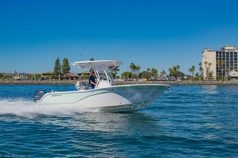 Slide: The Image of 2021 Sea Fox 248 Commander boat cruising on a sunny day near a coastal cityscape. - 33
