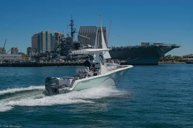 Slide: The Image of 2021 Sea Fox 248 Commander boat cruising near a harbor with cityscape background. - 45
