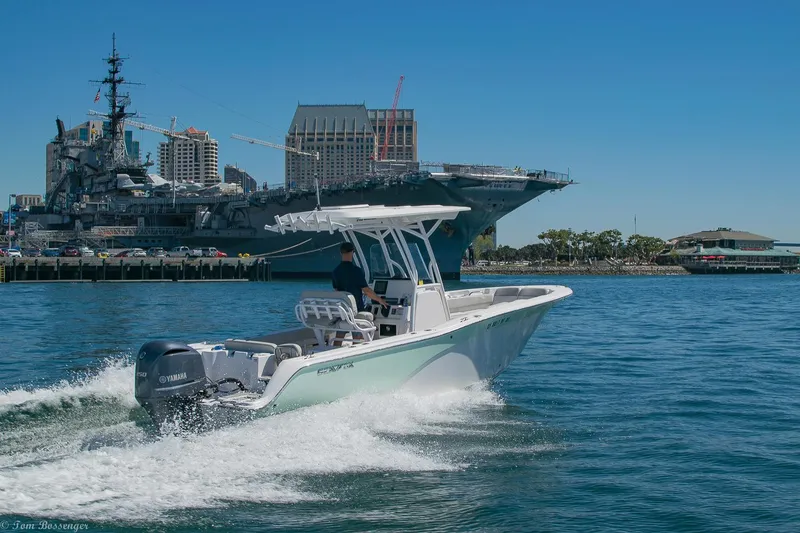 Slide: The Image of Sea Fox 248 Commander boat cruising near a harbor with a large ship in the background. - 49