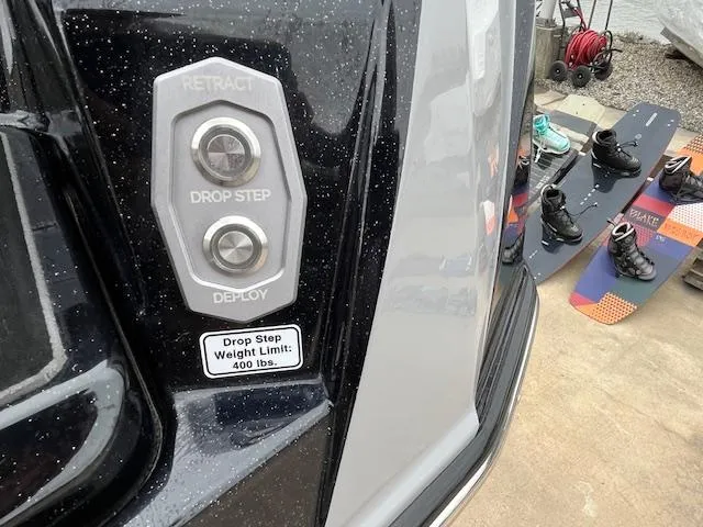 Slide: The Image of 2024 Supra SL boat with drop step controls, wakeboards, and boots nearby. - 12