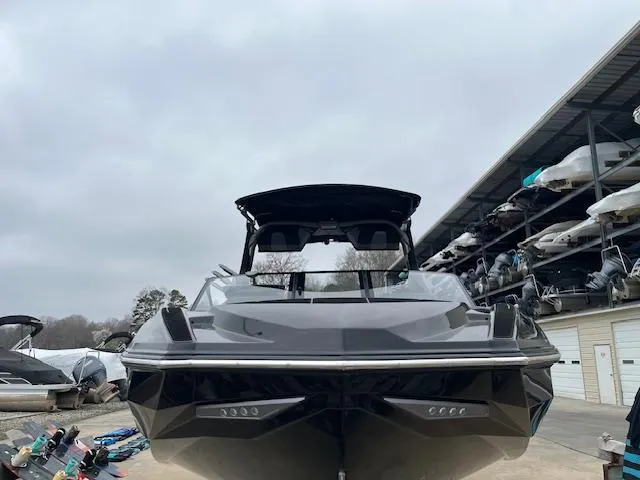 Slide: The Image of 2024 Supra SL boat in storage, front view, sleek design, overcast sky. - 15