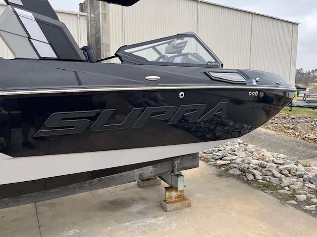 Slide: The Image of 2024 Supra SL boat in black, docked on a stand near a warehouse. - 17