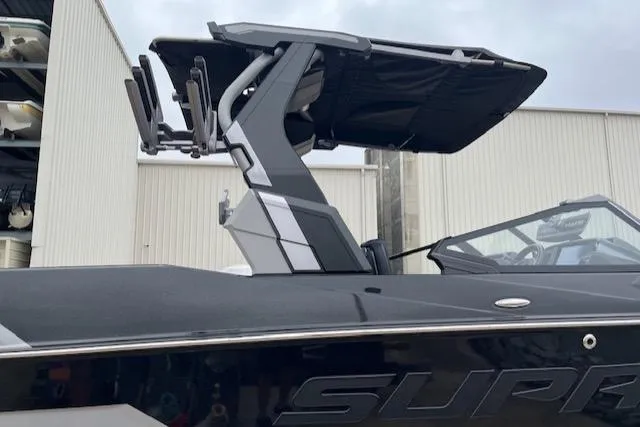 Slide: The Image of 2025 Supra SL boat with sleek design and modern features, docked near industrial buildings. - 2