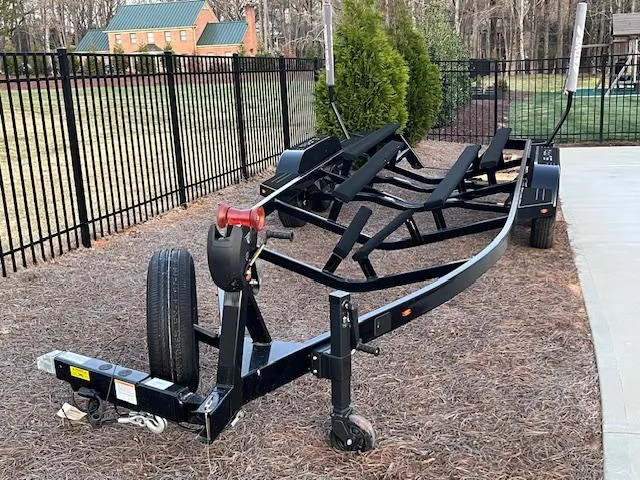 Slide: The Image of 2025 Supra SL boat trailer parked on mulch near a black fence. - 22