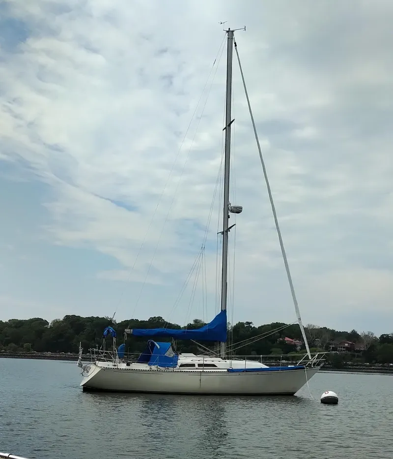 Slide: The Image of 1984 C&C 35 MK III sailboat anchored on calm water under a cloudy sky. - 2