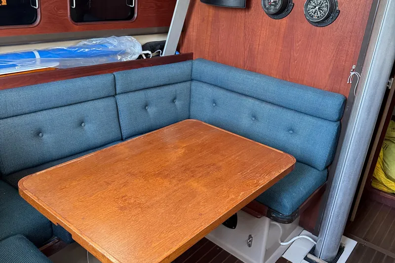 Slide: The Image of 1984 C&C 35 MK III sailboat interior with wooden table and blue cushioned seating. - 22