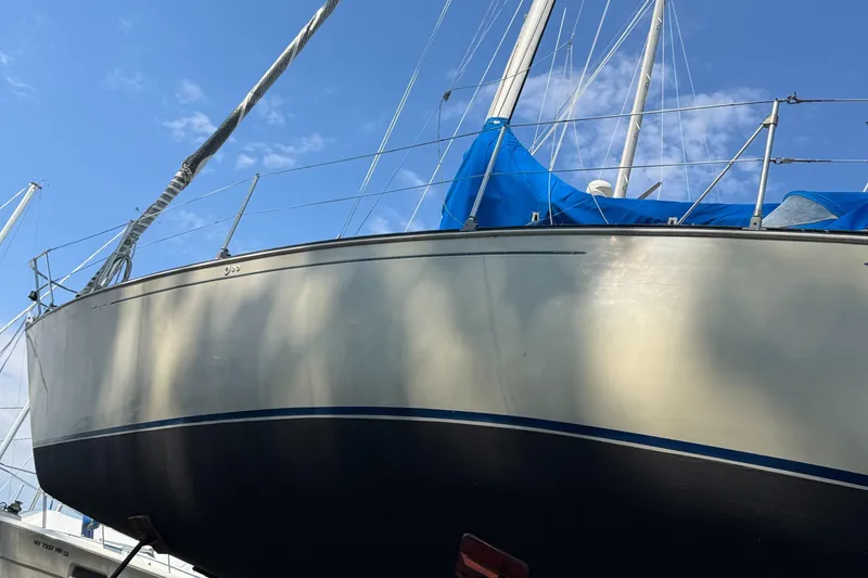 Slide: The Image of 1984 C&C 35 MK III sailboat with blue tarp, docked under clear sky. - 5