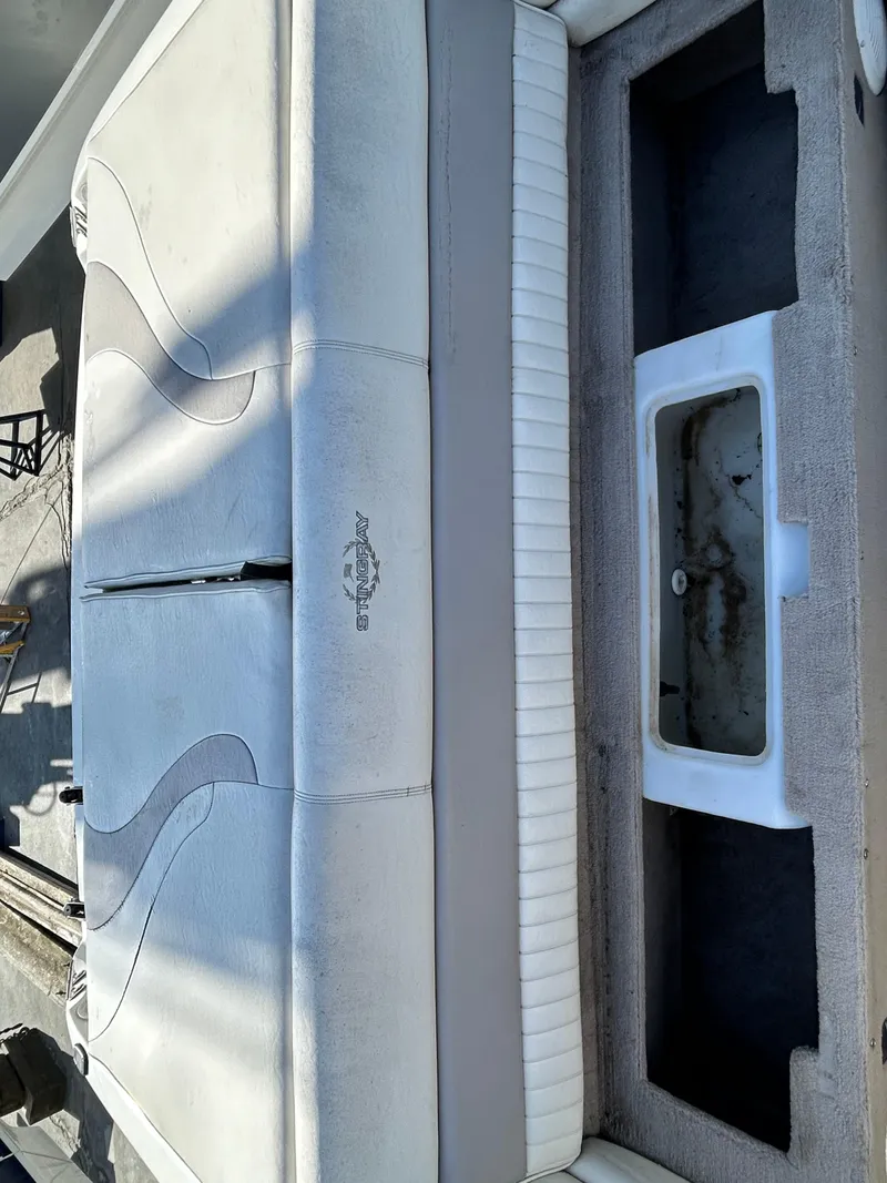 Slide: The Image of 2005 Stingray 195 FX boat interior with white cushioned seating and storage compartment. - 11