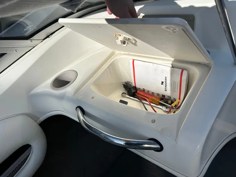 Slide: The Image of Open storage compartment in 2005 Stingray 195 FX boat with tools and manual. - 17