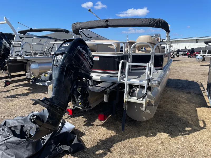 Slide: The Image of 2017 Sun Tracker BB18 pontoon boat with Mercury outboard motor, parked on dry land. - 4
