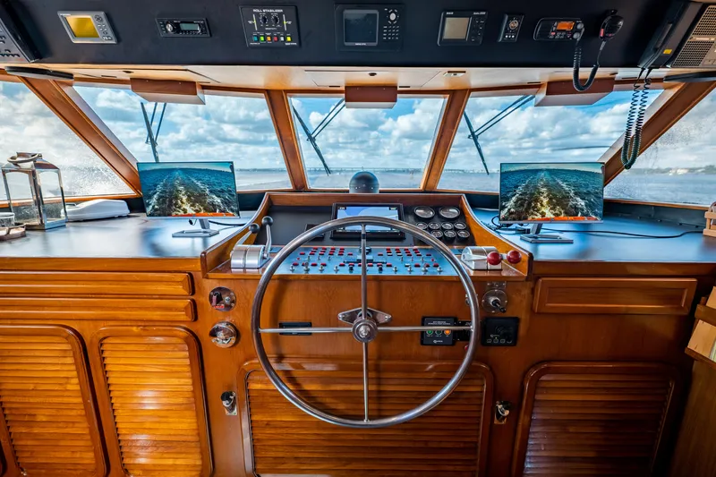 Slide: The Image of 1985 Cheoy Lee 90 Motor Yacht helm with wooden dashboard and dual navigation screens. - 41