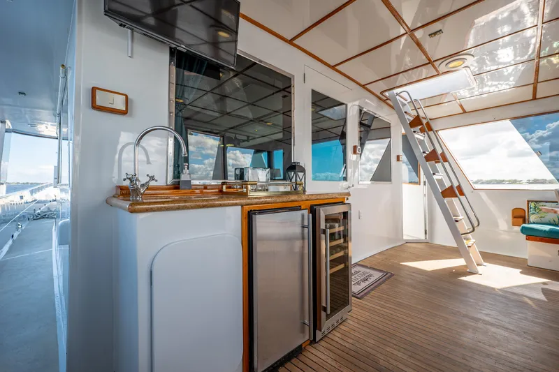 Slide: The Image of 1985 Cheoy Lee 90 Motor Yacht interior with kitchenette, stainless steel appliances, and wooden flooring. - 47