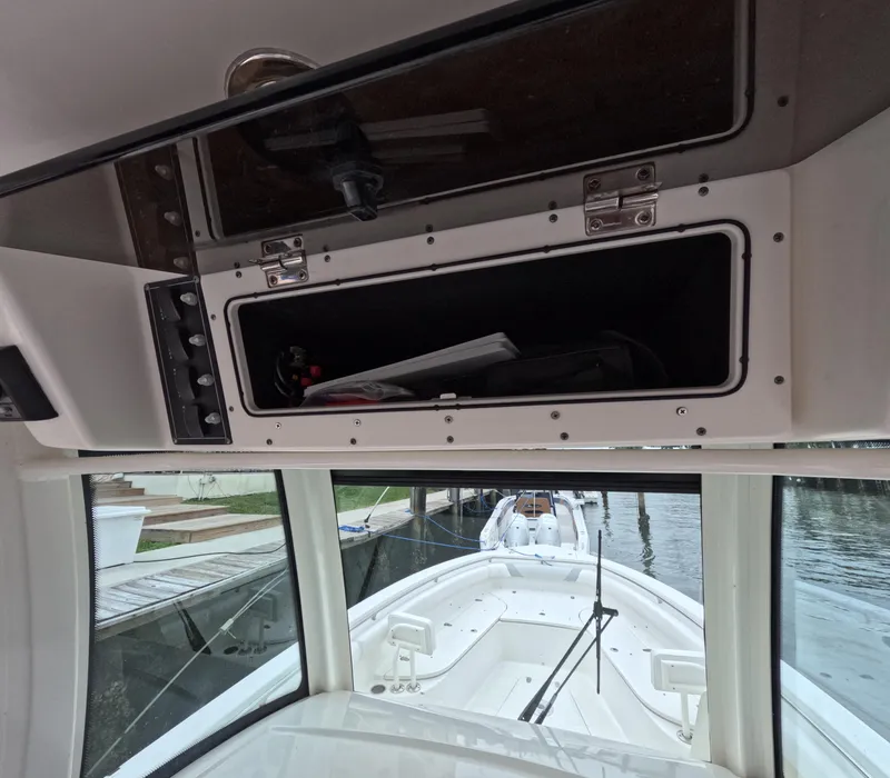 Slide: The Image of 2013 Boston Whaler 320 Outrage interior with open storage compartment and view of the deck. - 15