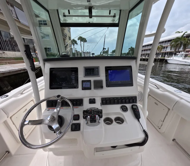 Slide: The Image of 2013 Boston Whaler 320 Outrage helm with steering wheel and navigation displays. - 2