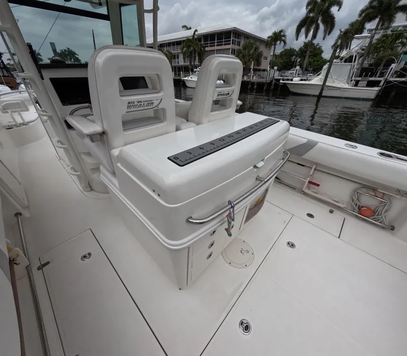 Slide: The Image of 2013 Boston Whaler 320 Outrage boat interior with seating and storage, docked near palm trees. - 20
