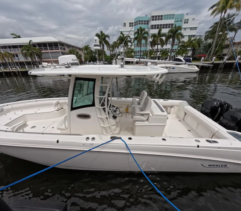 Slide: The Image of 2013 Boston Whaler 320 Outrage boat docked in marina, surrounded by palm trees. - 24