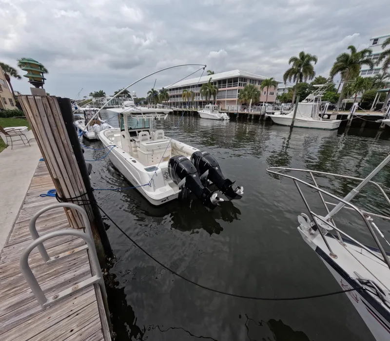 Slide: The Image of 2013 Boston Whaler 320 Outrage docked in a marina with palm trees and cloudy sky. - 27