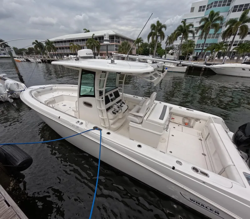 Slide: The Image of 2013 Boston Whaler 320 Outrage boat docked in marina, surrounded by palm trees. - 30