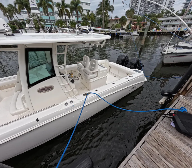 Slide: The Image of 2013 Boston Whaler 320 Outrage docked in a marina, surrounded by water and palm trees. - 31