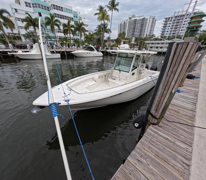 Slide: The Image of 2013 Boston Whaler 320 Outrage docked in a marina with palm trees and buildings. - 32