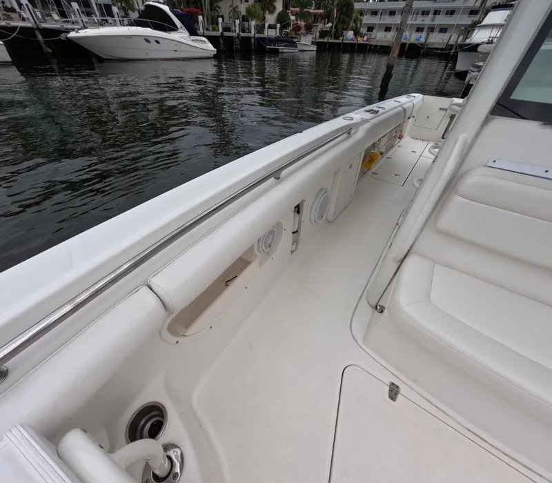 Slide: The Image of 2013 Boston Whaler 320 Outrage boat interior with white seating and docked yachts nearby. - 36