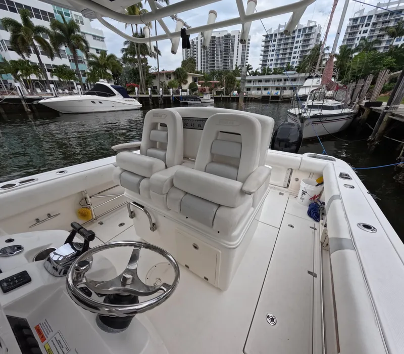 Slide: The Image of 2013 Boston Whaler 320 Outrage boat interior with helm and seating, docked near yachts. - 41
