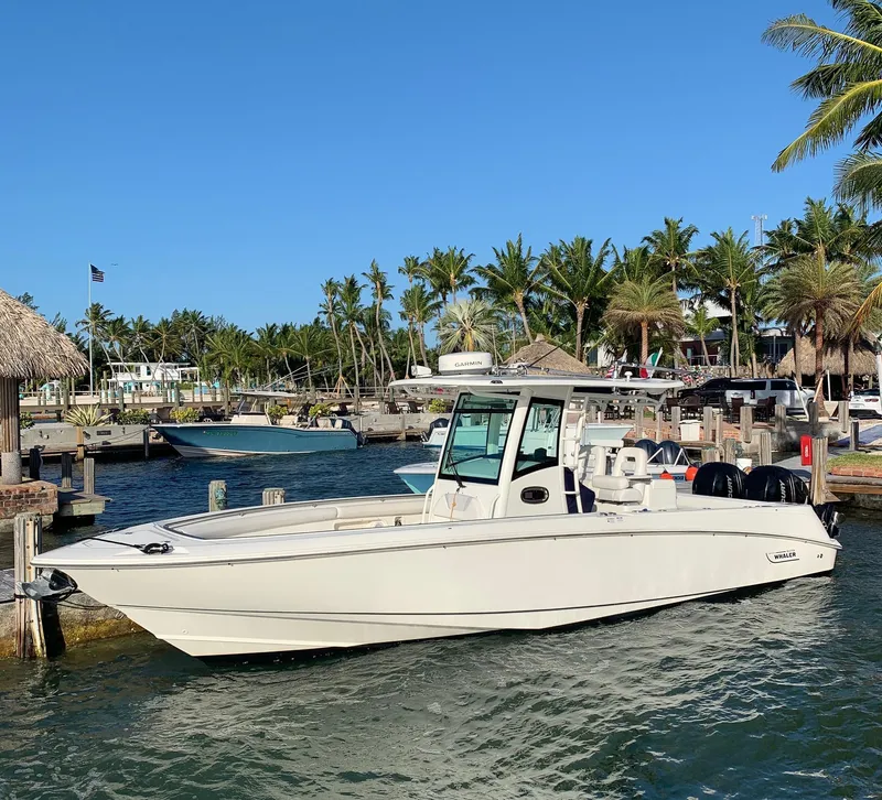 Slide: The Image of 2013 Boston Whaler 320 Outrage boat docked near palm trees and clear blue sky. - 49