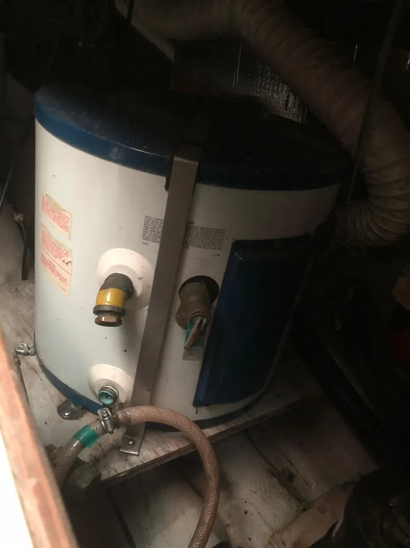 Slide: The Image of 1984 Tartan T-33 water heater with hoses and connections in a dimly lit space. - 15