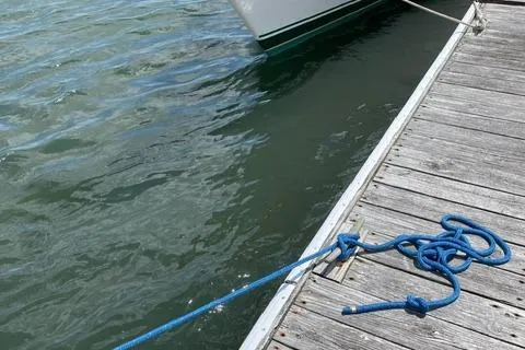 Slide: The Image of Docked Tartan T-33 sailboat from 1984, secured with blue rope on wooden pier. - 31
