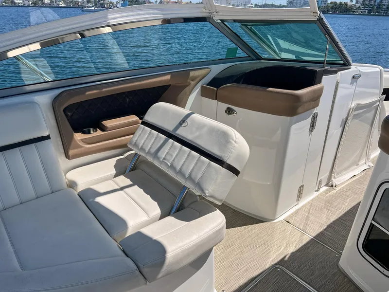 Slide: The Image of 2016 Cobalt 336 boat interior with white seating and brown accents, docked by the water. - 12