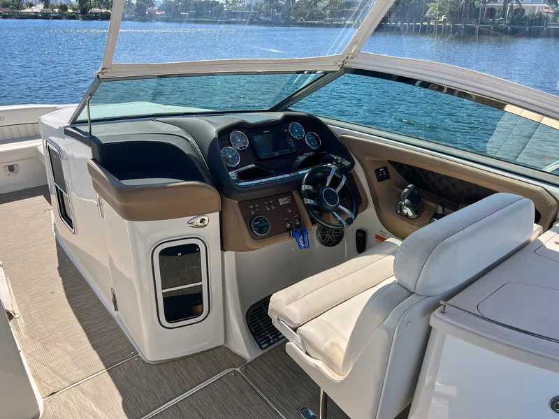 Slide: The Image of 2016 Cobalt 336 boat cockpit with steering wheel, dashboard, and comfortable seating by the water. - 14