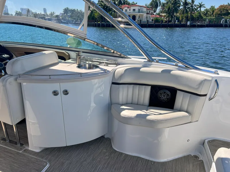 Slide: The Image of 2016 Cobalt 336 boat interior with seating and sink, docked by waterfront homes. - 18
