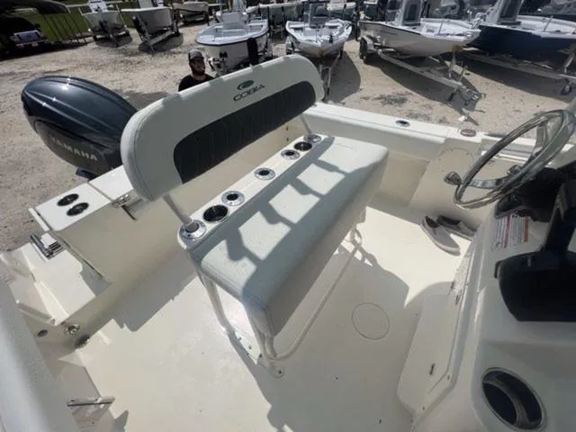 Slide: The Image of 2024 Cobia 220 CC boat interior with seating and steering wheel, displayed outdoors. - 11