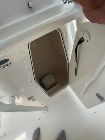 Slide: The Image of 2024 Cobia 220 CC boat storage compartment with open door, showcasing interior space. - 12
