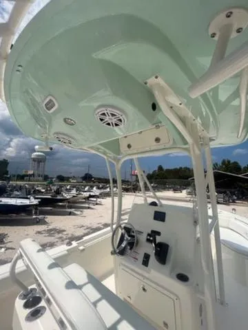 Slide: The Image of 2024 Cobia 220 CC boat interior with helm, speakers, and overhead canopy. - 8
