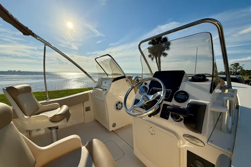 Slide: The Image of 2025 Scout 195 Sport Dorado boat interior with steering wheel, seats, and scenic water view. - 14