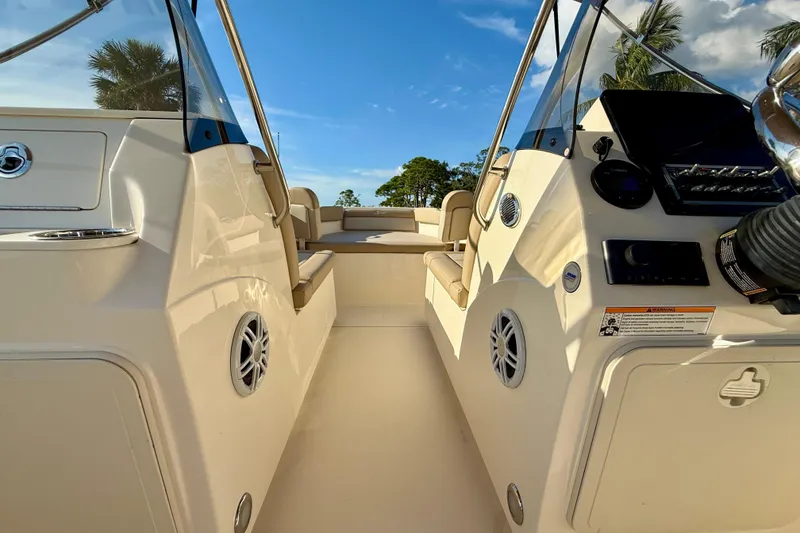 Slide: The Image of 2025 Scout 195 Sport Dorado boat interior with seating and control panel, under clear blue sky. - 20
