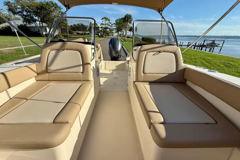 Slide: The Image of 2025 Scout 195 Sport Dorado boat interior with beige seating, near a scenic waterfront. - 31