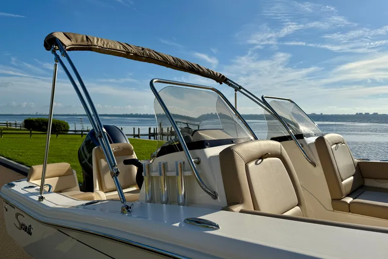 Slide: The Image of 2025 Scout 195 Sport Dorado boat with beige seating, docked by a scenic waterfront. - 38