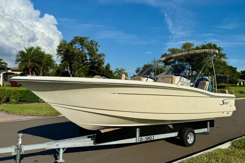 Slide: The Image of 2025 Scout 195 Sport Dorado boat on trailer, parked on a sunny street. - 4
