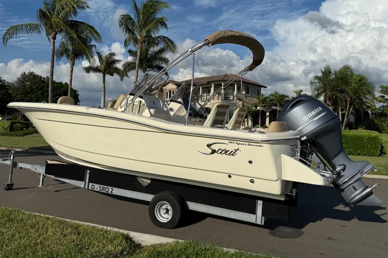 Slide: The Image of 2025 Scout 195 Sport Dorado boat on trailer, parked near palm trees and luxury home. - 6
