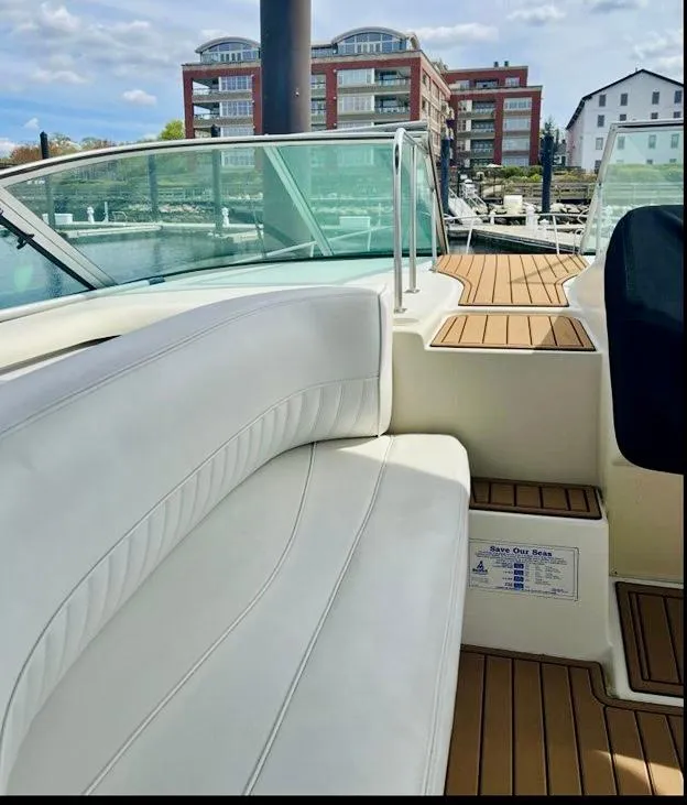 Slide: The Image of 2000 Cruisers Yachts 3772 Express with white seating and wooden deck, docked near buildings. - 5